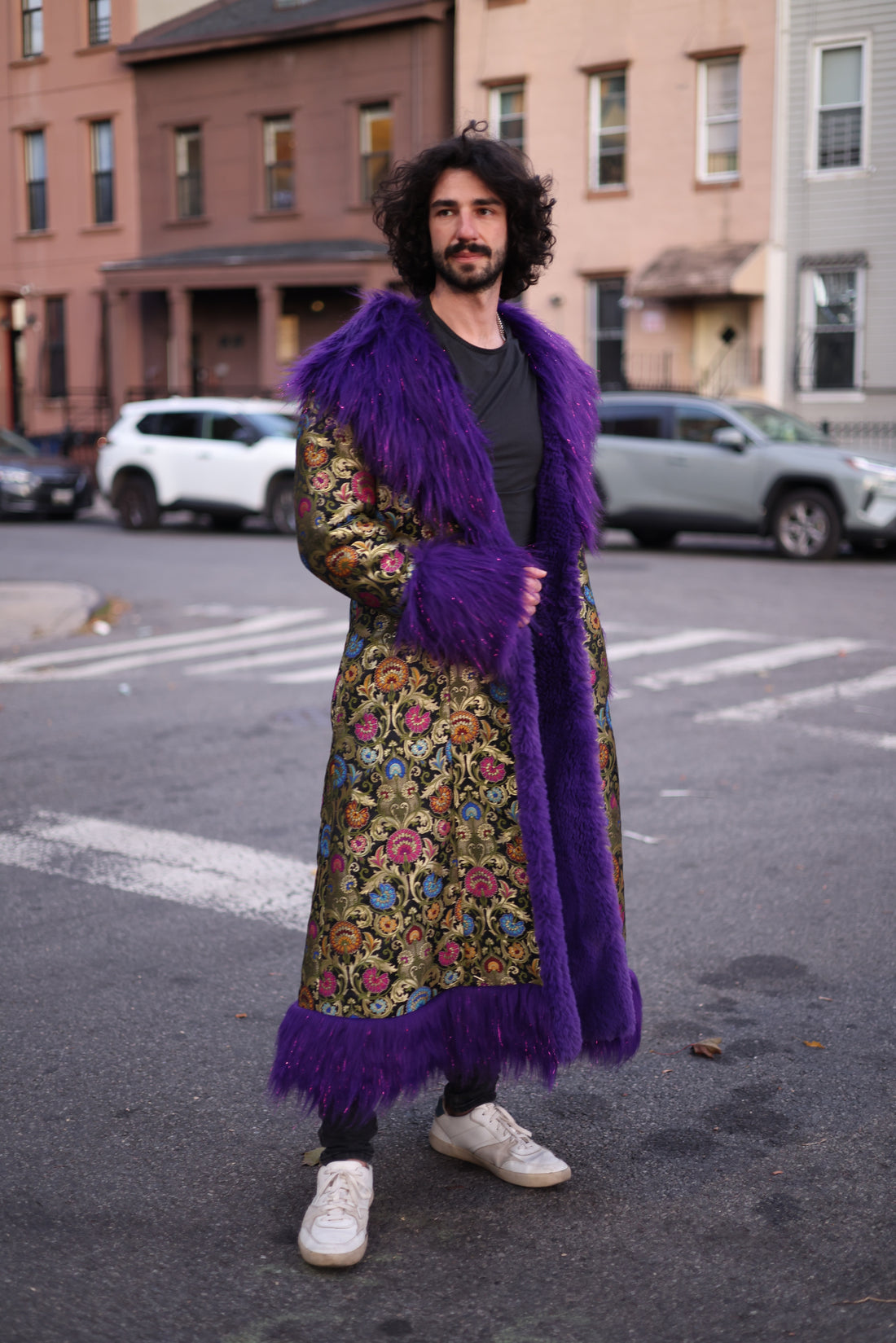 Back view of the PURPLE RAIN full-length silk brocade coat with a colorful floral pattern, oversized purple faux fur collar, cuffs, and hem trim.